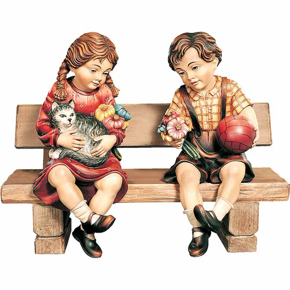 Niños sentados en un banco con balón y gatito